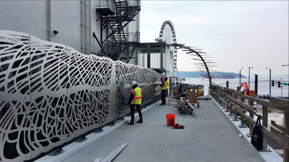 The screen being installed along the bridge deck with the fern in the background