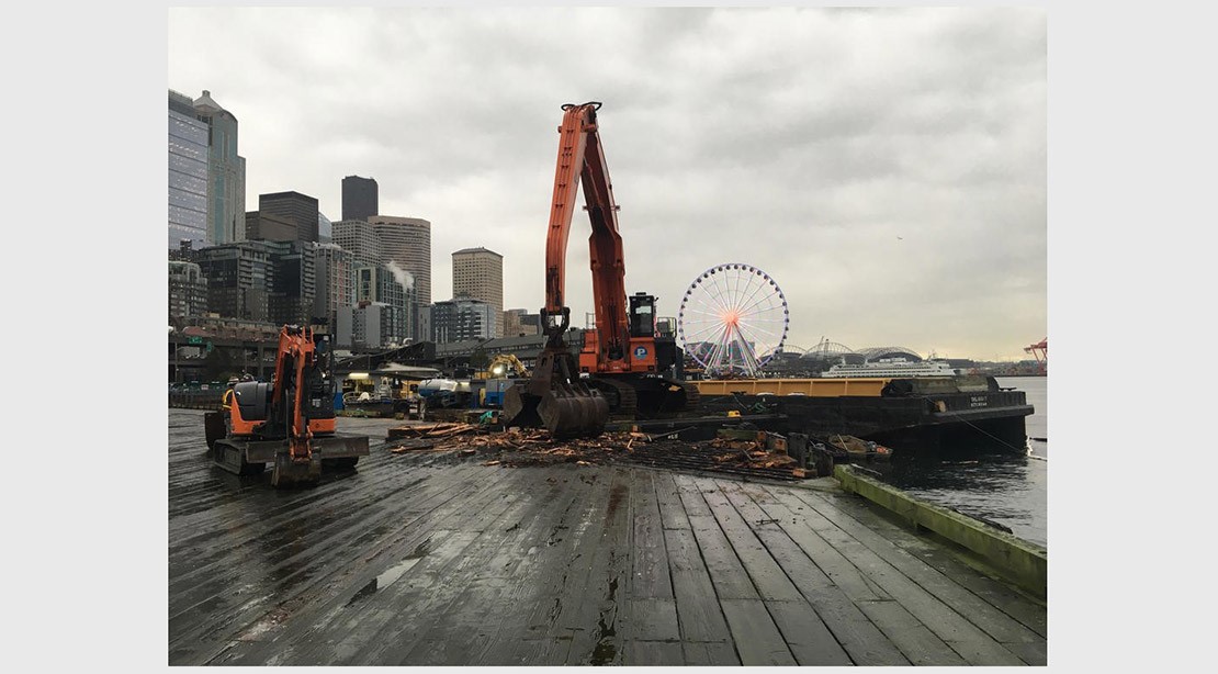 Photo of excavator removing timber decking on the old pier. 