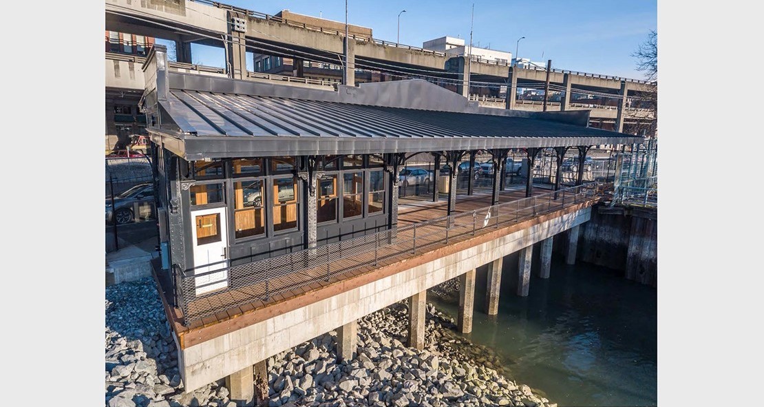 Photo of the reinstalled Washington Street Boat Landing Pergola, an outdoor structure consisting of columns that support a roofing grid of beams and rafters that is located by the water at the end of South Washington Street