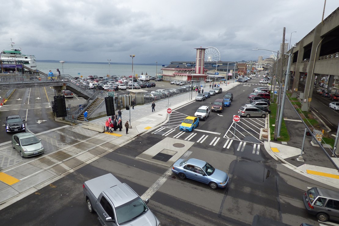Photo shows vehicles exiting from a ferry to Alaskan Way South, a road that has one lane in each direction. 
